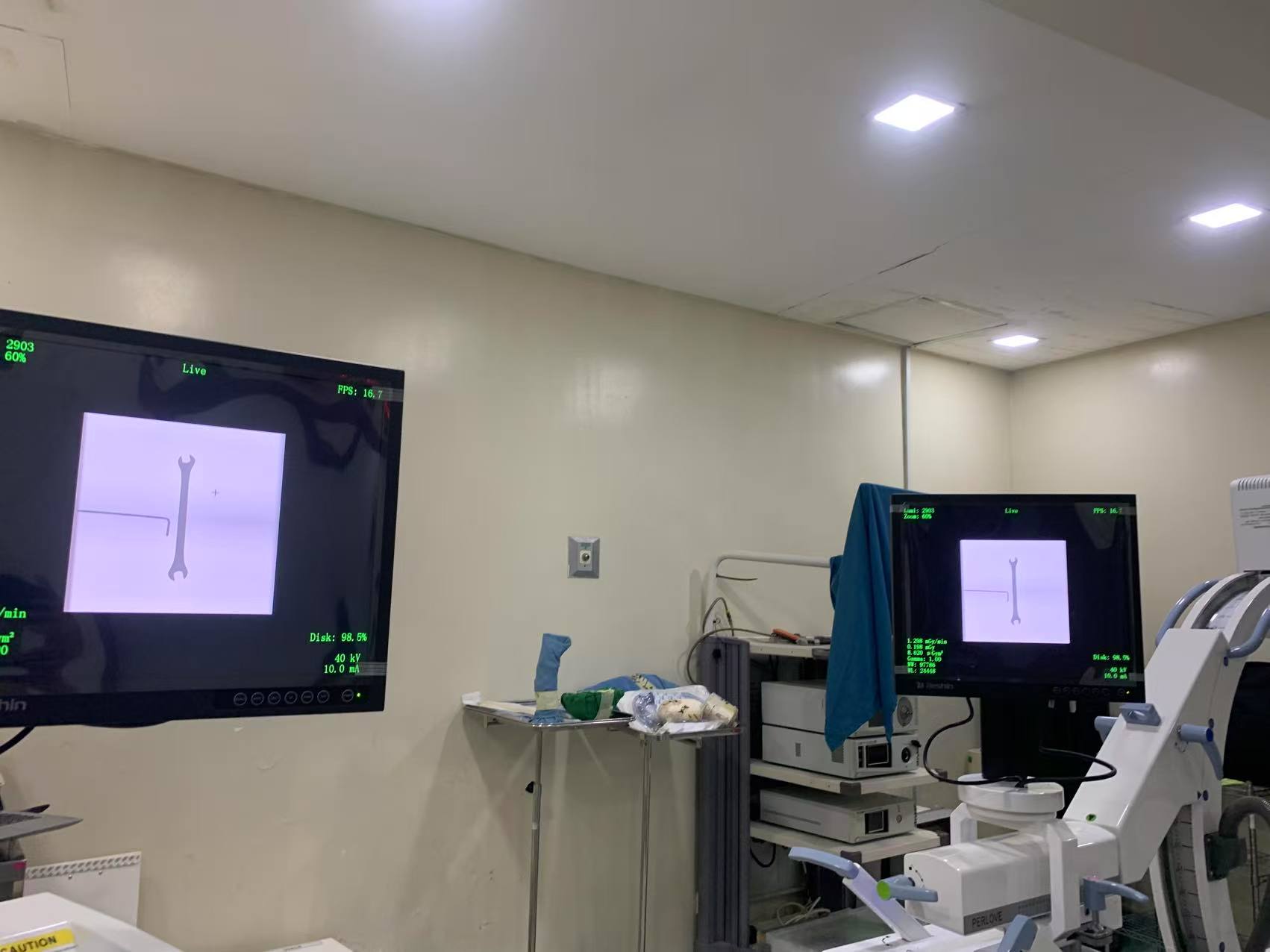 Monitors duals en una sala de radiologia que mostren una imatge n&iacute;tida i sense fantasmes d'una clau anglesa durant una prova d'exposici&oacute; al bra&ccedil; C.