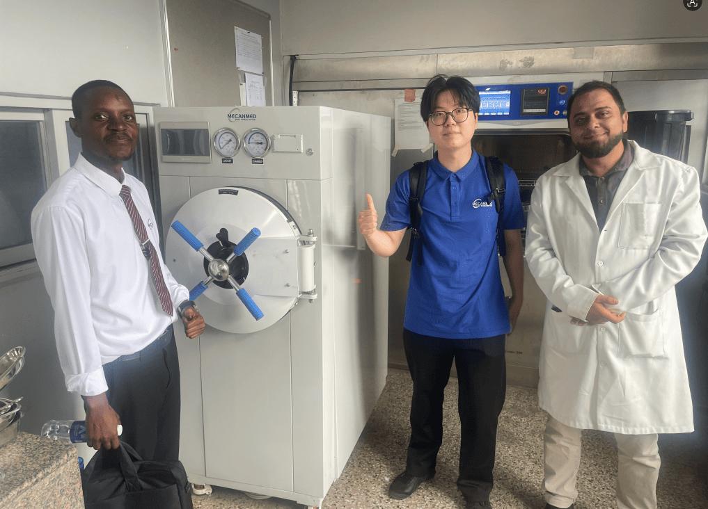 L'equip de MeCanMed inspecciona un gran esterilitzador d'autoclau horitzontal d'alta temperatura amb personal cl&iacute;nic d'una cl&iacute;nica de Z&agrave;mbia.